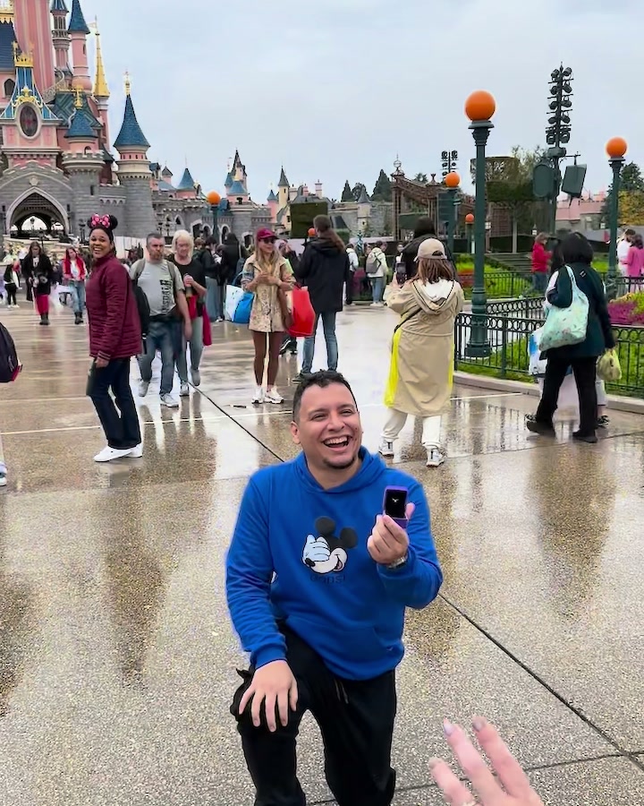 José arrodillado proponiendo matrimonio a Dou frente al castillo de Disneyland Paris